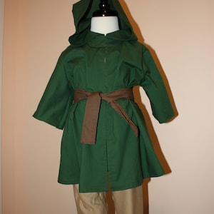 May include: A green hooded robe with a brown belt, worn over tan pants. The robe has a long, flowing design and a pointed hood.
