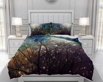 May include: A bed set featuring a duvet cover and two pillowcases. The bedding displays a dark, silhouetted forest scene with a colorful gradient sky of blues, oranges, and purples. The design includes twinkling lights and a few perched birds.