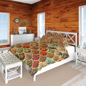 May include: A white bed with a colorful patterned duvet cover and matching pillowcases. The duvet cover features a geometric design with red, blue, green, and yellow colors. The bed is in a room with wood paneling on the walls.