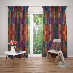 May include: Two colorful curtains with a geometric pattern of red, orange, yellow, green, blue, and purple. The curtains are hung on a white wall and a window with a view of trees is visible behind them.