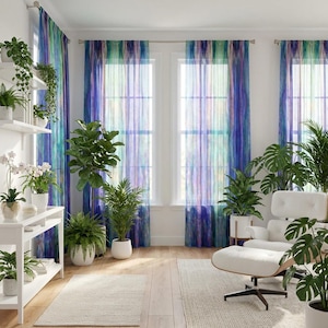 May include: Sheer curtains with a watercolor effect in shades of blue, green, and purple hang in front of windows. The room is decorated with various potted plants, a white chair, and a white shelving unit. Two off-white rugs are on the wooden floor.