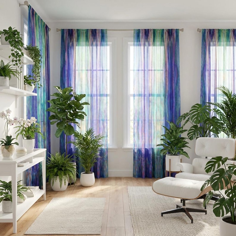 May include: Sheer curtains with a watercolor effect in shades of blue, green, and purple hang in front of windows. The room is decorated with various potted plants, a white chair, and a white shelving unit. Two off-white rugs are on the wooden floor.