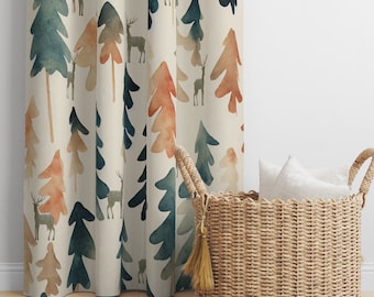 May include: A beige curtain with a watercolor pattern of trees and deer. The curtain is hung on a white wall and a wicker basket with white pillows is in front of it.