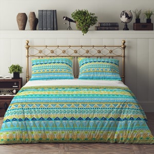 May include: A blue and green patterned duvet cover with geometric designs. The duvet cover is on a bed with a gold metal headboard and two matching pillowcases.