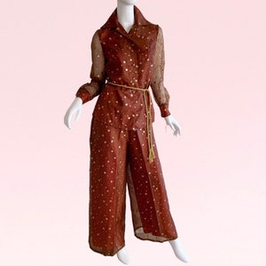 May include: A brown and gold patterned jumpsuit with a long-sleeved shirt and wide-leg pants. The jumpsuit has a gold chain belt.