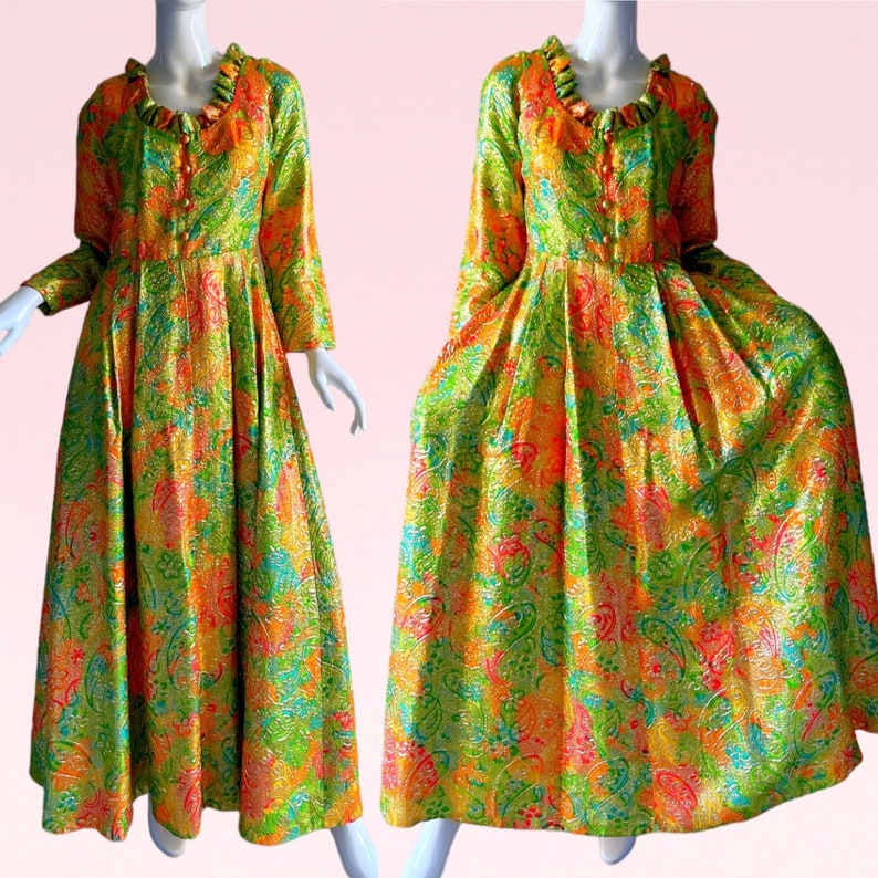 May include: A long, flowing green, orange, and pink patterned dress with a ruffled collar and long sleeves. The dress has a fitted bodice and a full skirt.