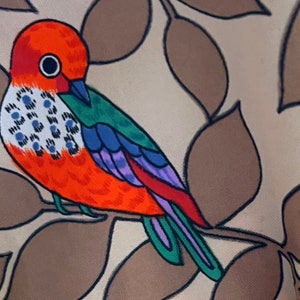 May include: A colorful bird with orange, red, green, blue, and purple feathers is perched on a branch with brown leaves. The bird has a large, round eye.
