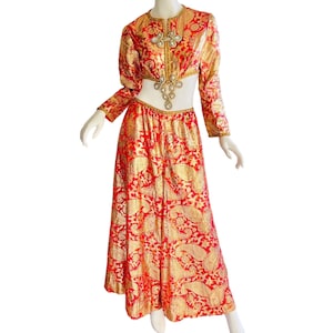 Może przedstawiać: Dwuczęściowy strój z czerwonego i złotego brokatu, składający się z długiej spódnicy i krótkiego topu. Top ozdobiony jest złotą i kryształową aplikacją.