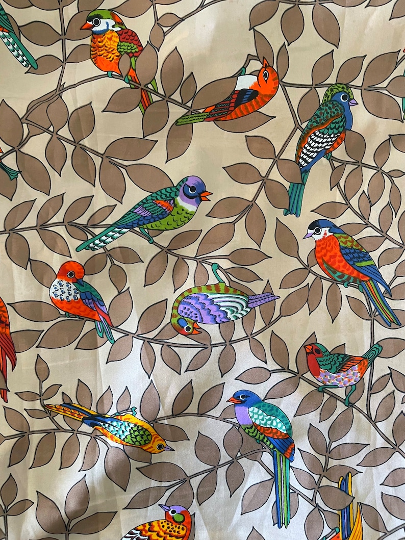 May include: A beige fabric with a repeating pattern of colorful birds on brown leafy branches. The birds are stylized and have different colors and patterns.