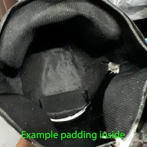 May include: Close-up of the inside of a black helmet with gray padding. The padding is designed to protect the wearer's head.