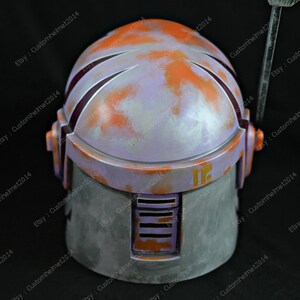 May include: A purple and orange painted helmet with a weathered look. The helmet has a raised number "16" on the side.