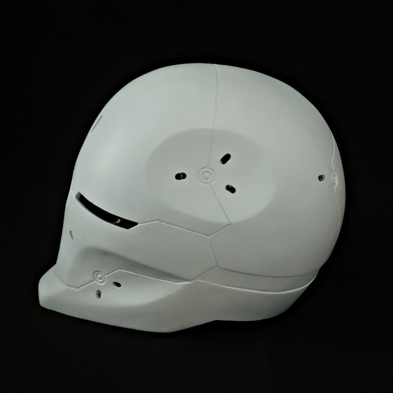 May include: A white helmet with a futuristic design. The helmet has a smooth, rounded top and a textured, segmented lower section. There are several small holes on the top and sides of the helmet.