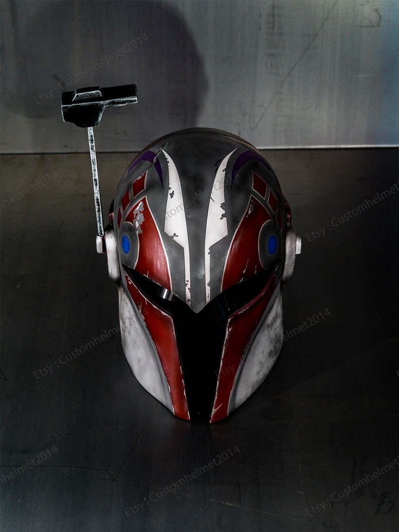May include: A red, white, and gray helmet with a black visor and a purple and white design. The helmet has a small antenna on top.