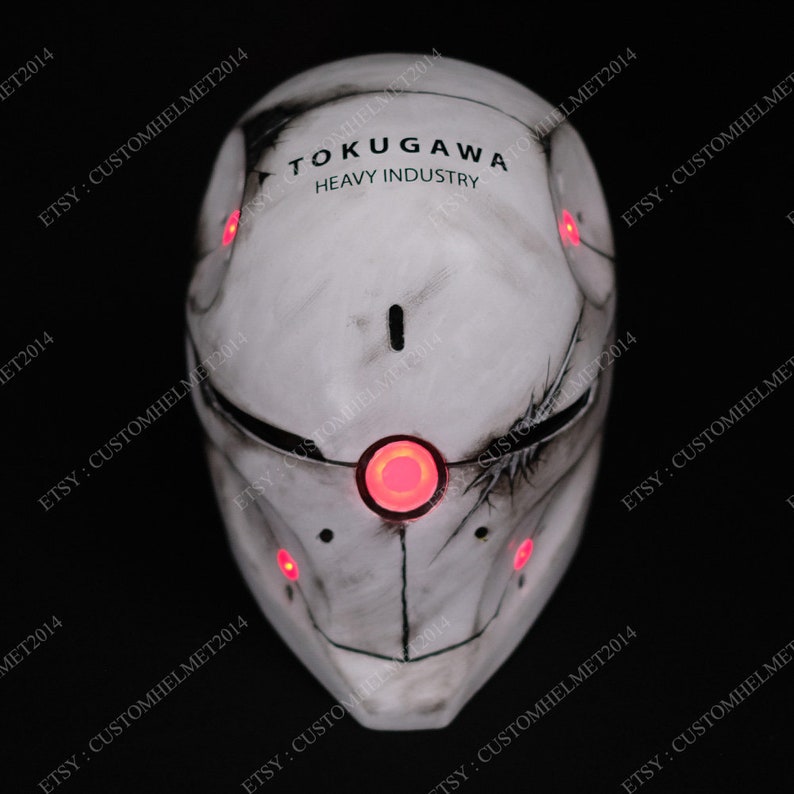 May include: A white helmet with a weathered, distressed look. The helmet has red LED lights and the text "TOKUGAWA HEAVY INDUSTRY" printed on the front.