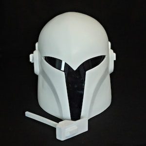 May include: White plastic helmet with a black visor and a white plastic accessory attached to the bottom.