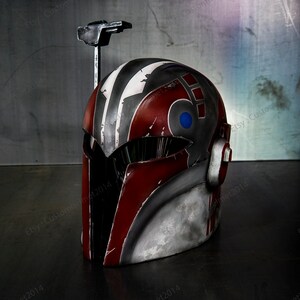 May include: A red, gray, and white helmet with a blue and white design on the side. The helmet has a black visor and a metal antenna on top.