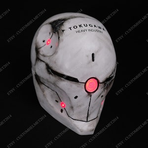 May include: A white helmet with red LED lights and the text "TOKUGAWA HEAVY INDUSTRY" on the side. The helmet is made of a hard plastic material and has a weathered, distressed look.