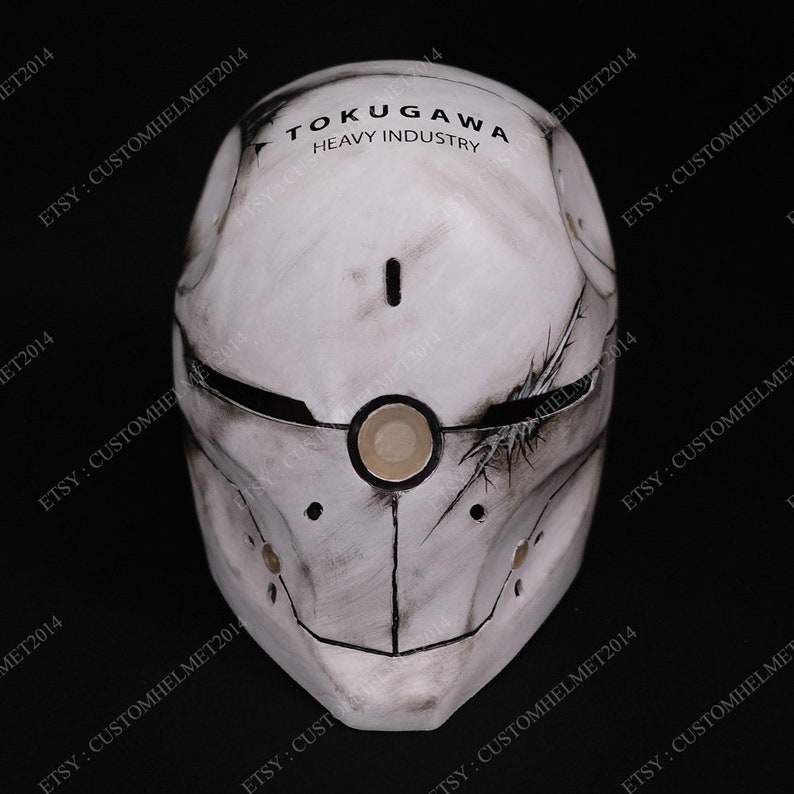 May include: A white helmet with a black and gray design. The helmet has a large, round, white eye piece and the text "TOKUGAWA HEAVY INDUSTRY" on the top.