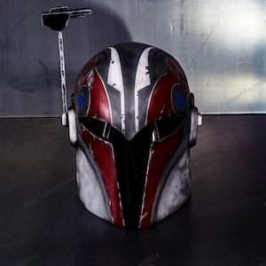 May include: A red, white, and black helmet with a blue visor and a black antenna. The helmet has a weathered, distressed look.