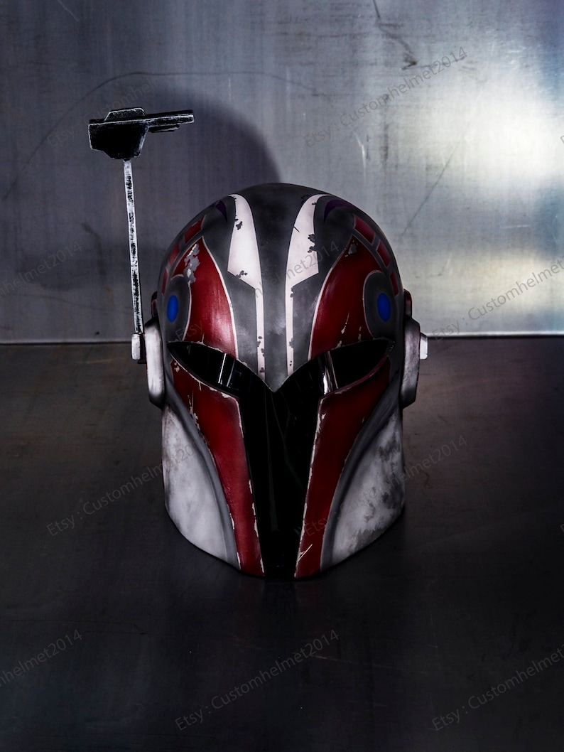 May include: A red, white, and black helmet with a blue visor and a black antenna. The helmet has a weathered, distressed look.
