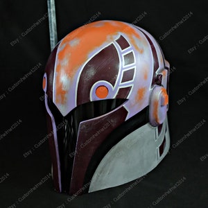 May include: A purple, orange, and silver helmet with a weathered finish. The helmet has a visor and a design on the side.