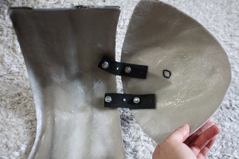 May include: Two pieces of a gray fiberglass motorcycle fairing with black metal brackets and screws. The fairing pieces are joined together.