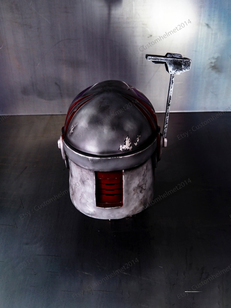 May include: A gray and red helmet with a weathered finish and a small antenna on top. The helmet has a red visor and a black stripe on the side. The helmet is sitting on a gray surface. Etsy: Customhelmet2014