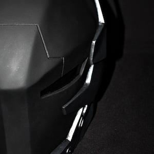 May include: A black helmet with silver accents. The helmet has a geometric design and a visor.