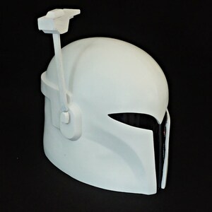 May include: A white plastic helmet with a black visor and a white antenna on top. The helmet has a textured surface and a smooth finish.