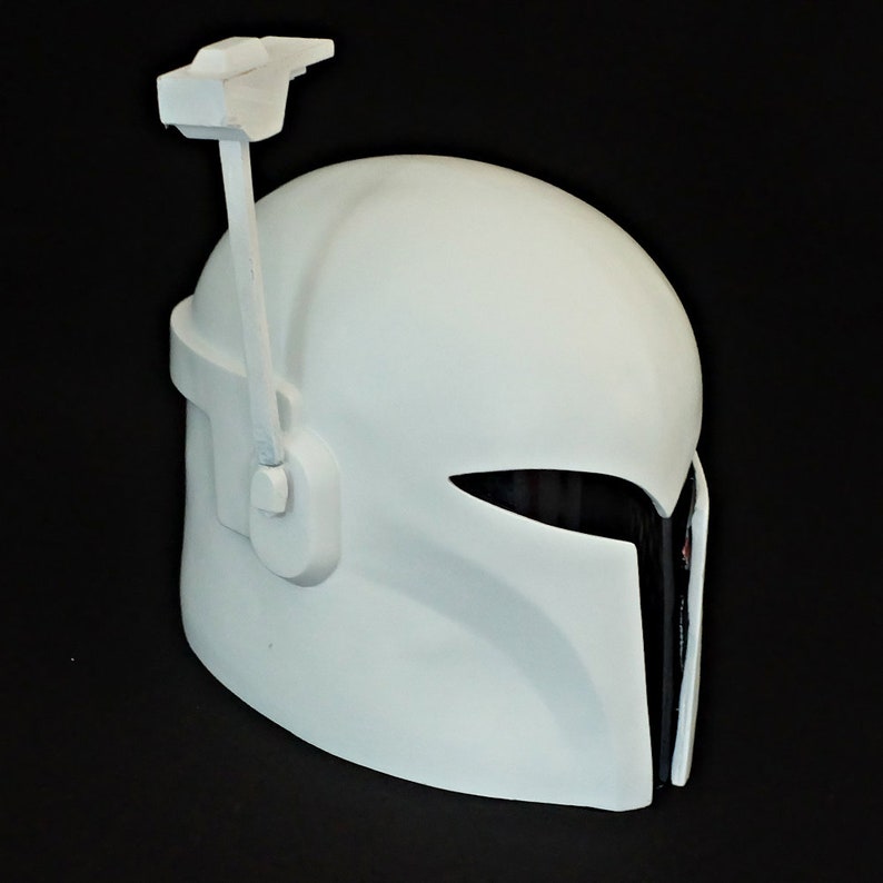 May include: A white plastic helmet with a black visor and a white antenna on top. The helmet has a textured surface and a smooth finish.