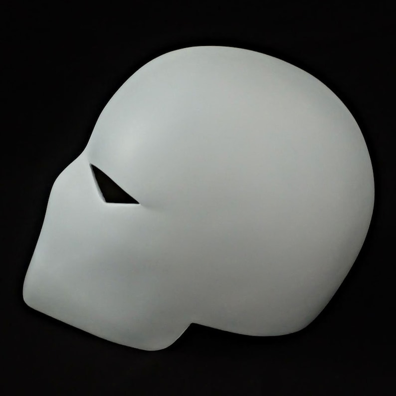 Pu&ograve; includere: Una maschera grigio chiaro con una superficie liscia e una singola apertura triangolare per gli occhi. La maschera &egrave; una forma solida e curva, probabilmente per cosplay o costumi, su sfondo nero.