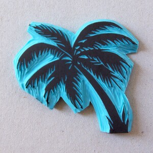 May include: A blue rubber stamp with a black silhouette of a palm tree. The stamp is designed for crafting and creating unique designs.