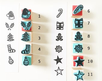 May include: A set of 11 Christmas-themed rubber stamps on wooden blocks. The stamps feature various holiday icons, including a stocking, a candy cane, a snowflake, a star, a Christmas tree, a present, a gingerbread man, and a holly sprig.