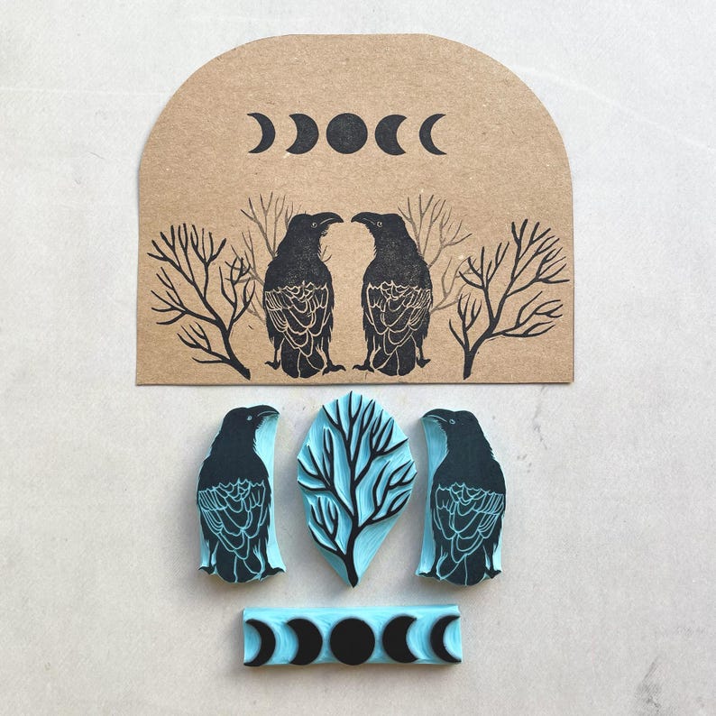 Puede incluir: Un conjunto de sellos de goma con tem&aacute;tica celestial y natural. Los sellos incluyen dos cuervos negros, un &aacute;rbol y fases lunares. Los sellos son de color negro y azul claro.