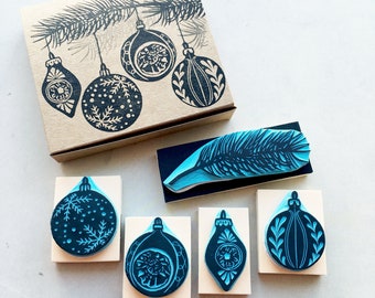 May include: Set of six wood mounted rubber stamps featuring a feather and five different Christmas ornaments. The stamps are black and white and have a vintage style.