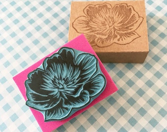 May include: Two rubber stamps with a floral design. The top stamp is brown and the bottom stamp is pink with a blue flower design.