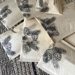 May include: A set of brown paper gift bags with black pine tree illustrations. The bags are decorated with a simple pine tree design and the text "MERRY & BRIGHT".