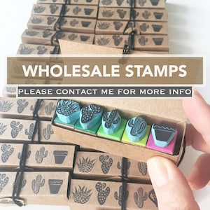 Può includere: Timbri all'ingrosso con disegni di cactus e succulente. I timbri sono in una scatola di cartone, con altre scatole impilate dietro. Il testo "WHOLESALE STAMPS" è visibile nell'immagine.