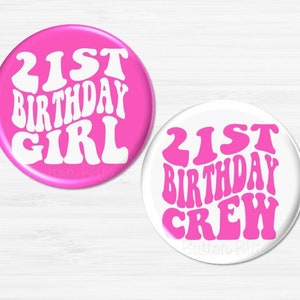 May include: Two round buttons with the text "21st Birthday Girl" in white on a pink background and "21st Birthday Crew" in pink on a white background.