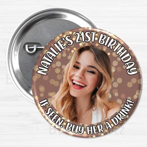 May include: A round, metallic button with a pin back. The button features a photo of a smiling woman with the text "NATALIE'S 21ST BIRTHDAY" and "IF SEEN, BUY HER A DRINK!" in a circular design around the photo.