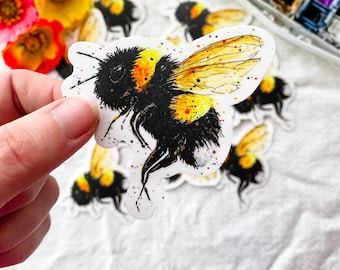 May include: A set of watercolor bee stickers with yellow and black stripes, and a white background with orange and red paint splatters.
