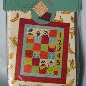 May include: A fabric swatch pack for a quilt pattern called "Monkey Trouble: 5 Funky Monkeys". The pack includes a sample of the fabric and a diagram of the quilt pattern. The quilt pattern features monkeys, bananas, and numbers.