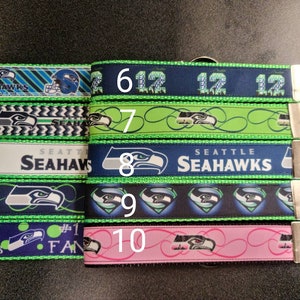 May include: Ten different keychains featuring the Seattle Seahawks logo. The keychains are made of green, blue, and white ribbon with different designs. The keychains are numbered 1 through 10.