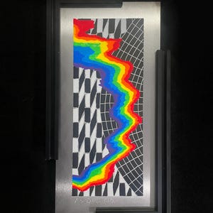 May include: Abstract art piece featuring a vibrant rainbow-colored wave against a black and white geometric background. The artwork is framed in a black frame with a silver metal backing. The artist's signature is visible at the bottom.