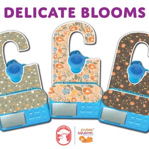 Pode incluir: Tr&ecirc;s dispositivos azuis com padr&otilde;es florais e o texto "DELICATE BLOOMS". Cada um tem uma ta&ccedil;a azul e um visor digital. Os desenhos florais apresentam flores laranja, brancas e verdes sobre fundos claros. O log&oacute;tipo Flying Squirrel &eacute; vis&iacute;vel.
