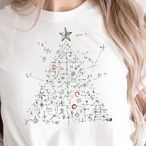 Op de afbeelding: Wit T-shirt met een zwart-witte afbeelding van een kerstboom gemaakt van wiskundige symbolen en vergelijkingen. De boom heeft een ster bovenop en rode kerstballen.