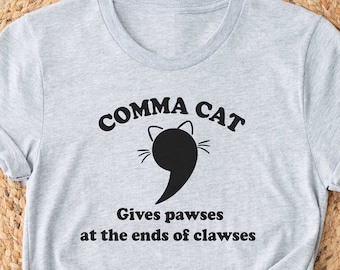 May include: Gray t-shirt with a black cat graphic and the text "Comma Cat Gives pawses at the ends of clawses".