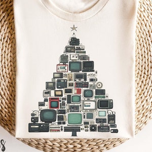 May include: A white t-shirt featuring a Christmas tree design made up of vintage televisions. The tree is decorated with a star on top and baubles.