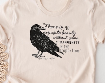 May include: A beige t-shirt with a black raven illustration and a quote from Edgar Allan Poe: "There is NO exquisite beauty without some STRANGENESS in the proportion."
