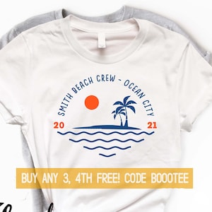 A minimalistic beach trip design in blue ink on a heather grey shirt. The top features text you can personalize over a circle that contains a palm tree and a sun over simple waves. The bottom has another line of text.